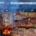 bbq pork ribs cooking on flaming grill shot with selective focus pork ribs on the grill