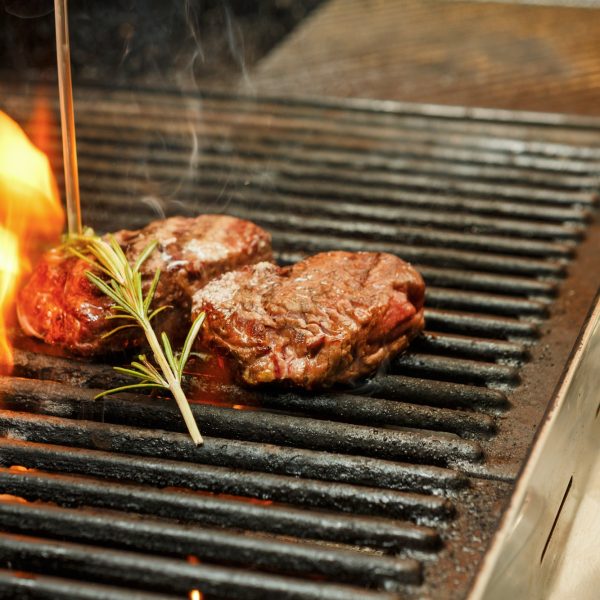 Meat steaks on grill on open fire